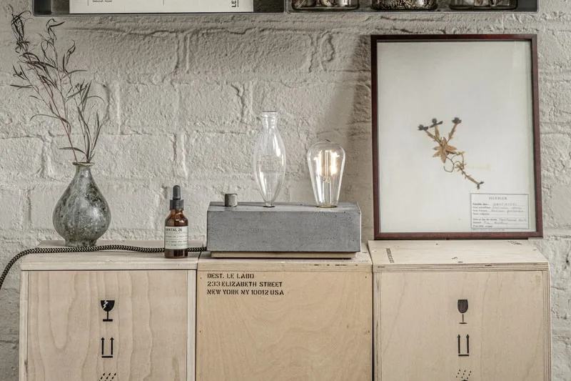 Intérieur avec déco sur boîtes en bois, lampe et cadre floral.