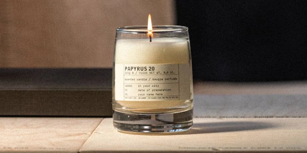 Bougie parfumée dans un verre transparent, étiquette beige.