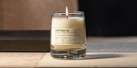 Bougie parfumée dans un verre transparent, étiquette beige.