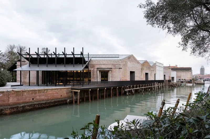Bâtiment moderne en brique au bord de l'eau, ciel nuageux.