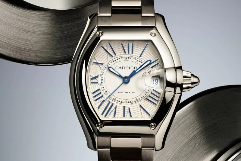 Montre Cartier avec bracelet métallique et chiffres romains bleus.