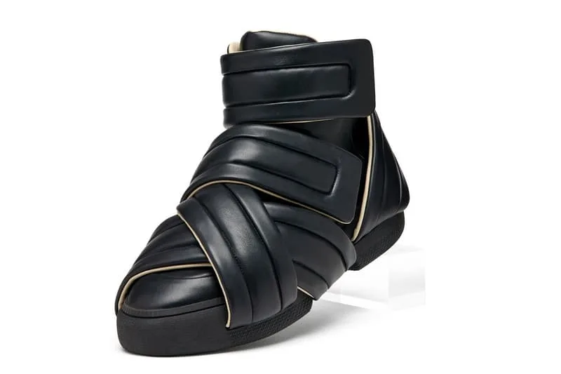 Chaussure en cuir noir avec fermeture éclair et bandes croisées.