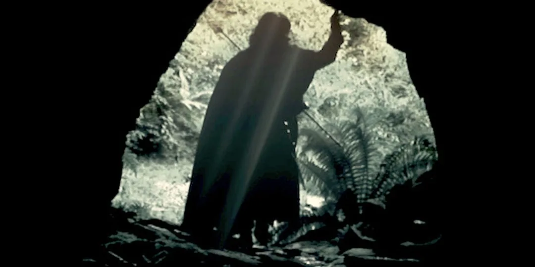 Silhouette d'une personne à l'entrée d'une grotte avec lumière derrière.