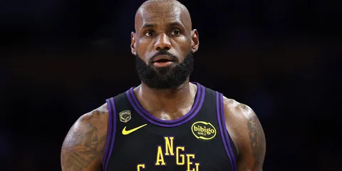 Joueur de basket en maillot noir et violet sur le terrain.