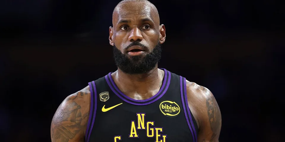 Joueur de basket en maillot noir et violet sur le terrain.