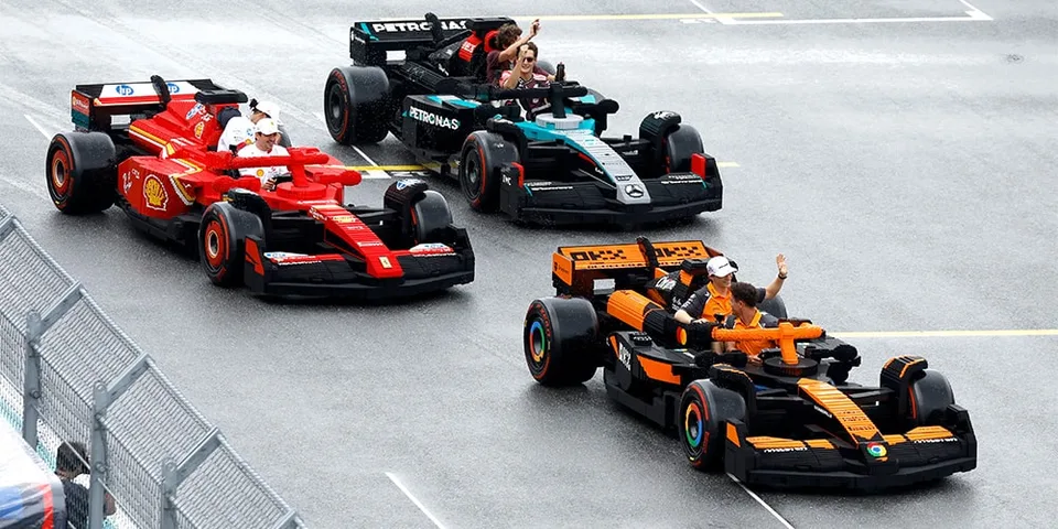 Voitures de course en briques LEGO sur une piste avec pilotes agitant la main.