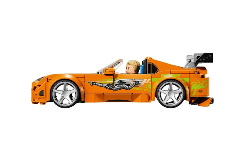 Une voiture jouet orange avec autocollants et spoiler arrière.