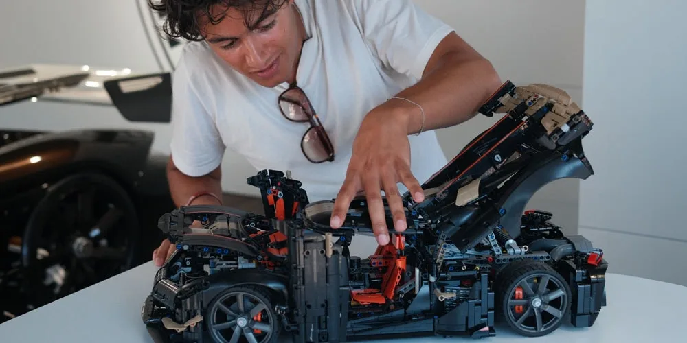 Personne inspectant une maquette de voiture détaillée, concentrée sur l'intérieur.