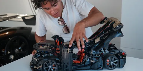 Personne inspectant une maquette de voiture détaillée, concentrée sur l'intérieur.