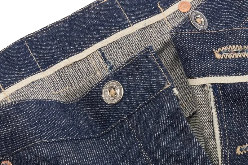 Vue détaillée de la ceinture d'un jean avec boutons et coutures visibles.