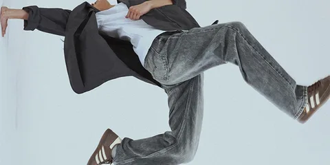 Personne en mouvement avec veste et jeans, fond blanc.