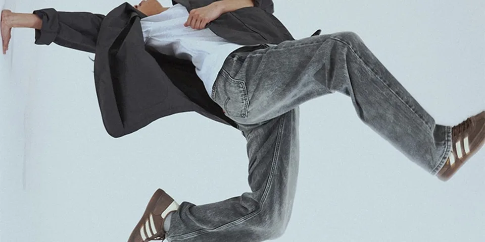 Personne en mouvement avec veste et jeans, fond blanc.