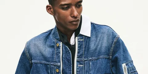 Homme en veste en jean bleu regardant vers le bas.