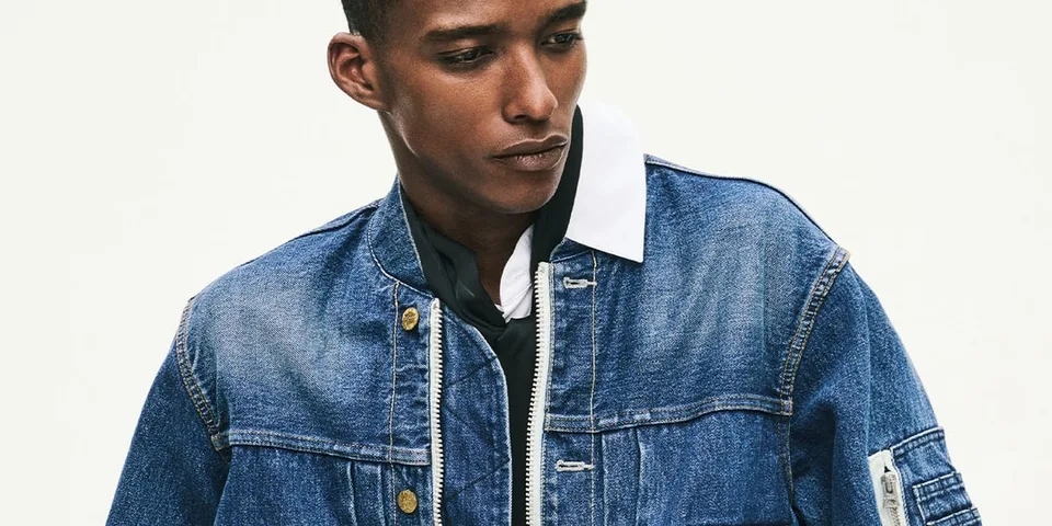 Homme en veste en jean bleu regardant vers le bas.