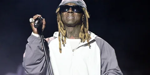 Personne avec dreadlocks, portant des lunettes de soleil et tenant un micro.