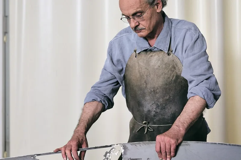 Homme travaillant le métal avec tablier dans un atelier.