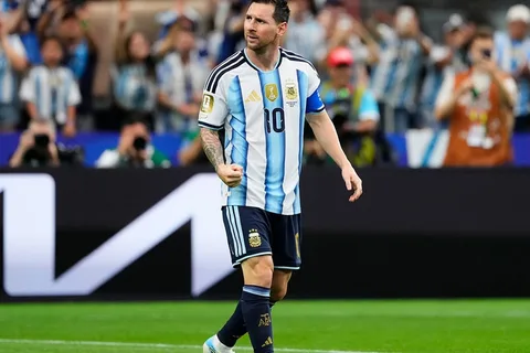 Joueur de football en tenue argentine célébrant sur le terrain.