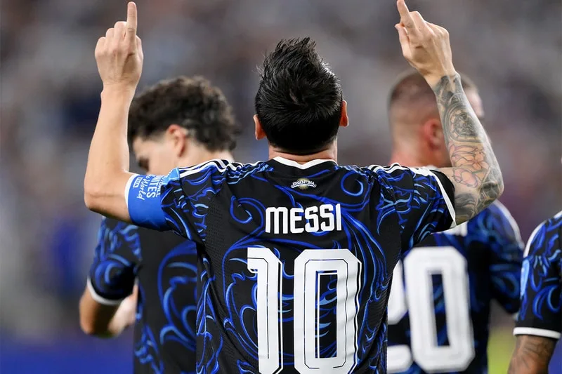 Joueur de football avec 'Messi' et '10' sur le maillot, bras levés.