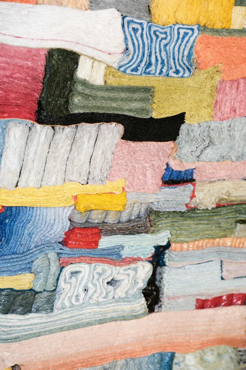 Empilement coloré de textiles ou papiers, motifs variés et entrelacés.