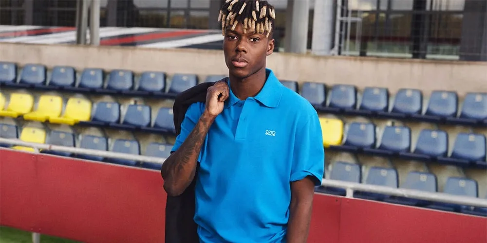 Homme avec chemise bleue et veste dans un stade vide.