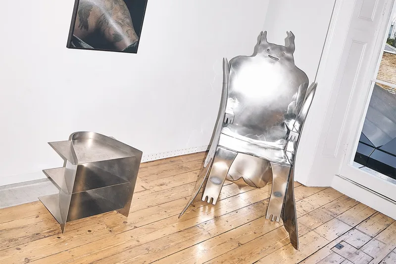 Chaise et meuble en métal sculpté dans une pièce lumineuse sur parquet