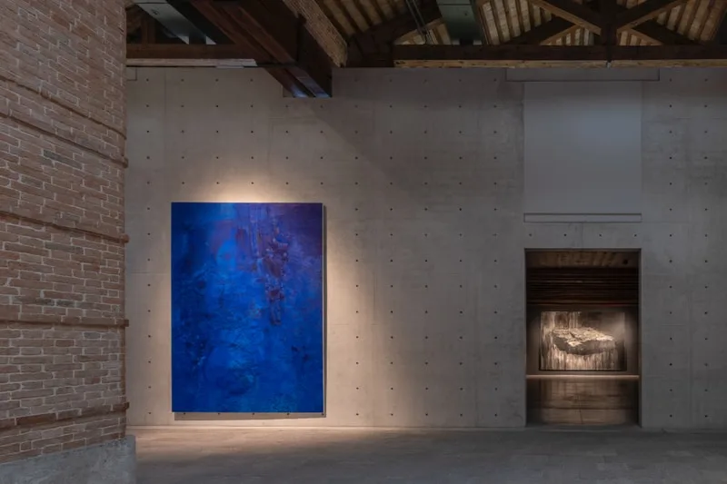 Exposition artistique avec une peinture bleue et une sculpture en arrière-plan.