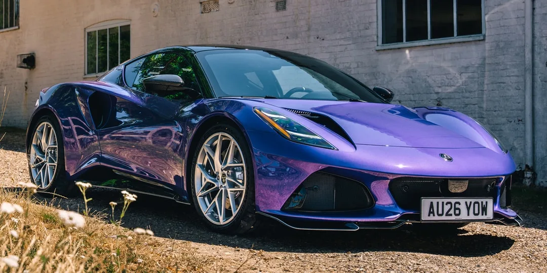 Voiture sport violette garée devant un bâtiment en brique.
