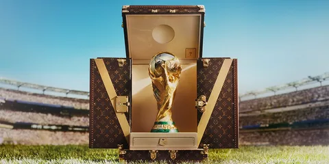 Trophée de la Coupe du Monde dans une mallette ouverte sur un stade