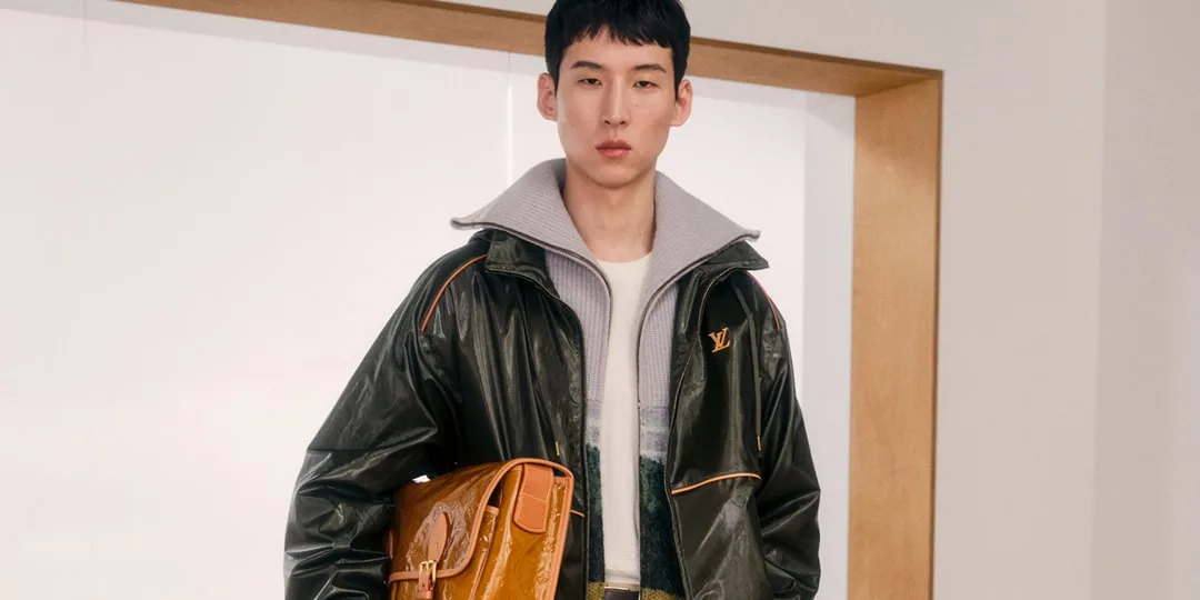 Homme avec veste noire et sac marron, intérieur moderne
