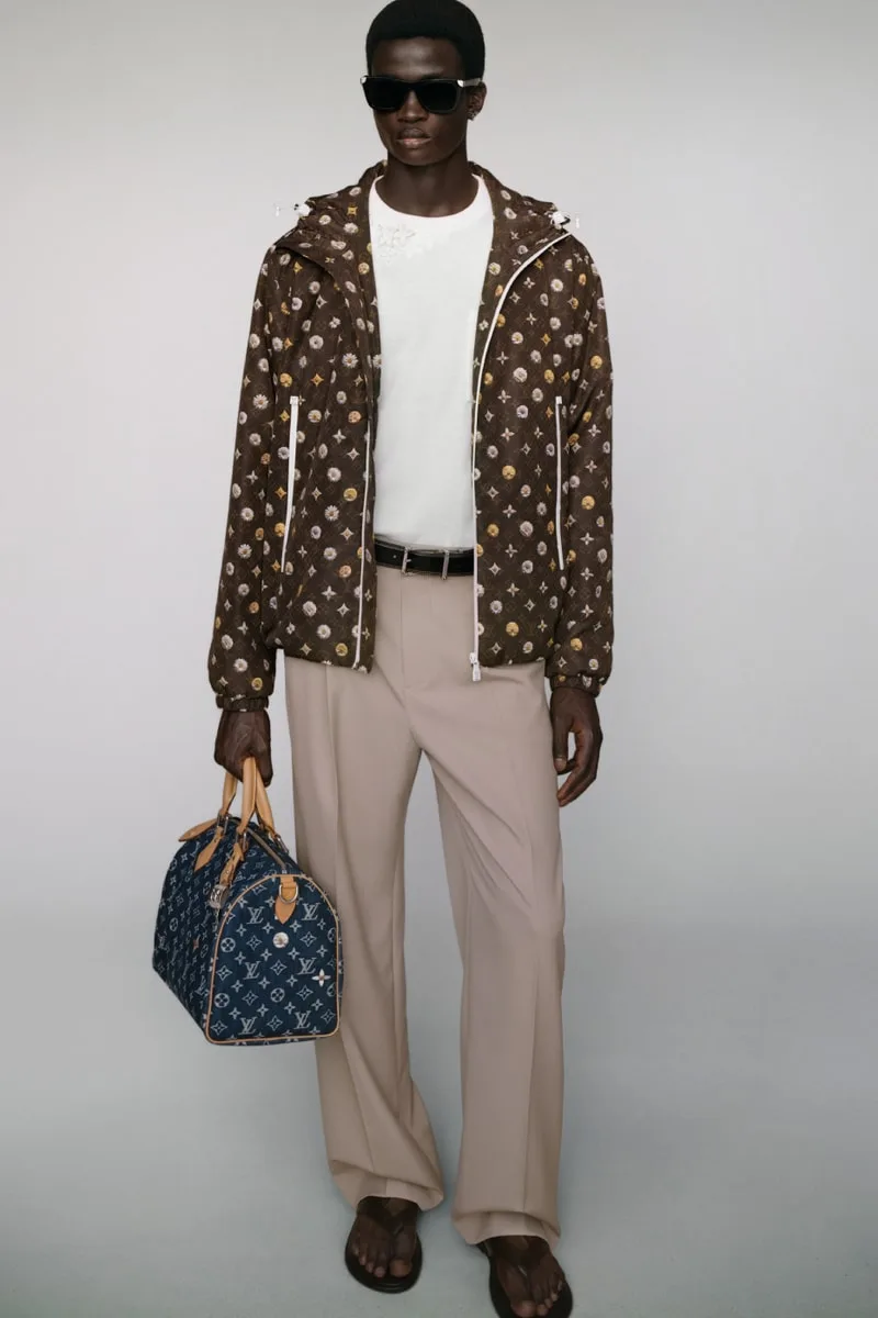 Homme en tenue Louis Vuitton avec un sac de voyage.
