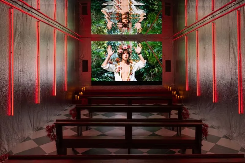Salle avec bancs, écran et décoration lumineuse rouge, forêt affichée sur l'écran.