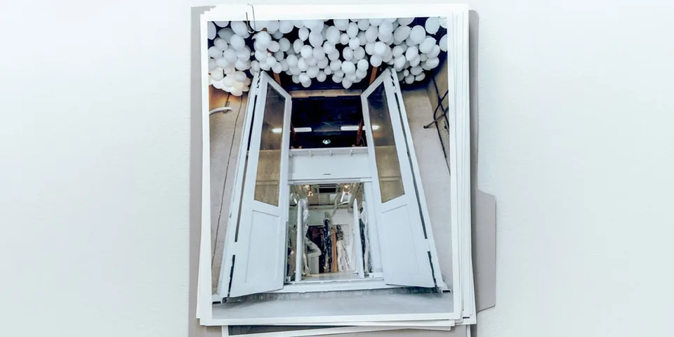 Portes ouvertes sous une installation de ballons blancs, photographiées depuis l’intérieur.