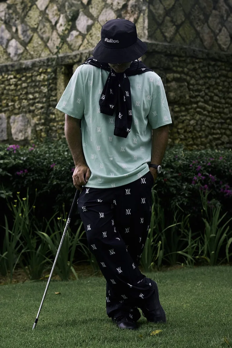 Homme en tenue de golf avec chapeau, sur pelouse verte.