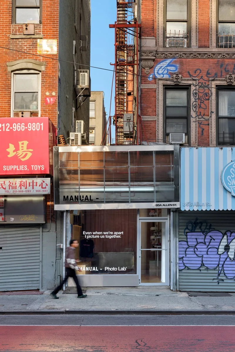 Boutique moderne dans rue animée avec personne passant devant.