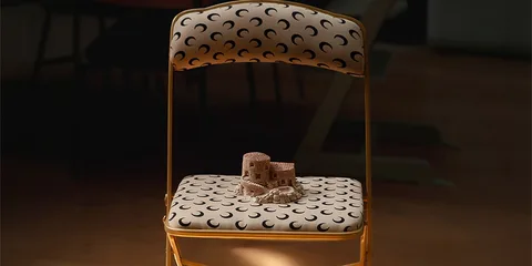 Chaise pliante avec motif croissant et château en sable en miniature.