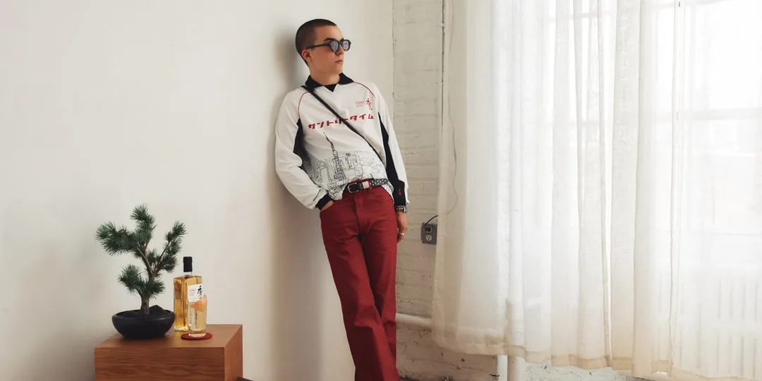 Homme en lunettes de soleil et pantalon rouge appuyé contre un mur.