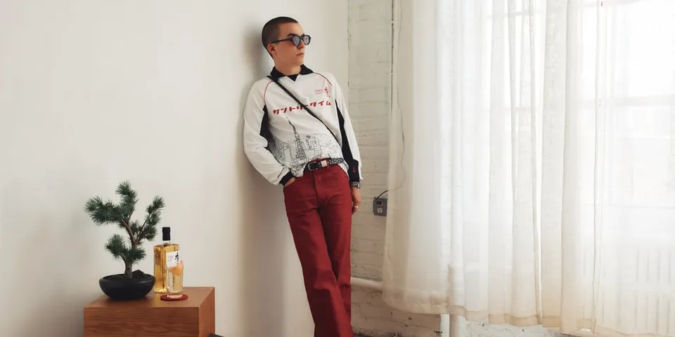 Homme en lunettes de soleil et pantalon rouge appuyé contre un mur.