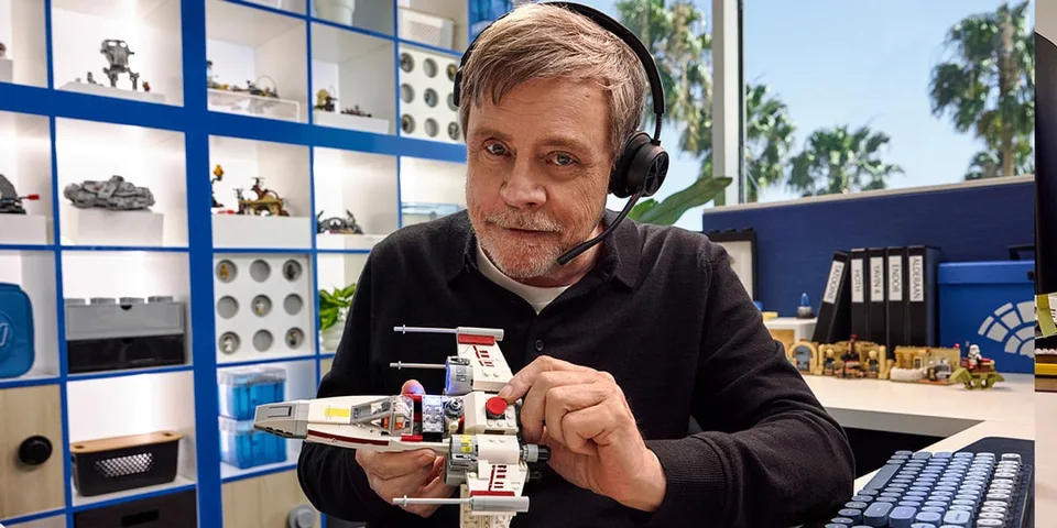 Homme avec casque construit un modèle de vaisseau spatial en briques.
