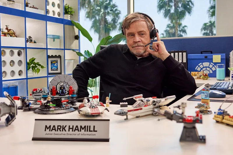 Homme avec casque jouant avec des jouets LEGO sur un bureau.