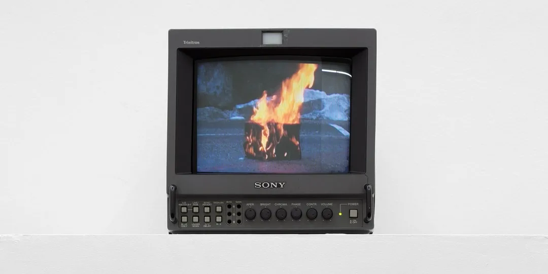 Un écran Sony montrant un feu brûlant dans un bidon sur la route.