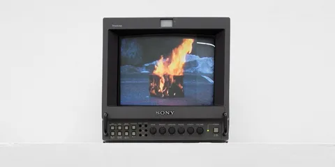 Un écran Sony montrant un feu brûlant dans un bidon sur la route.