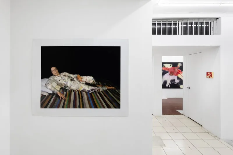 Galerie avec photographie d'une personne allongée et peinture abstraite.