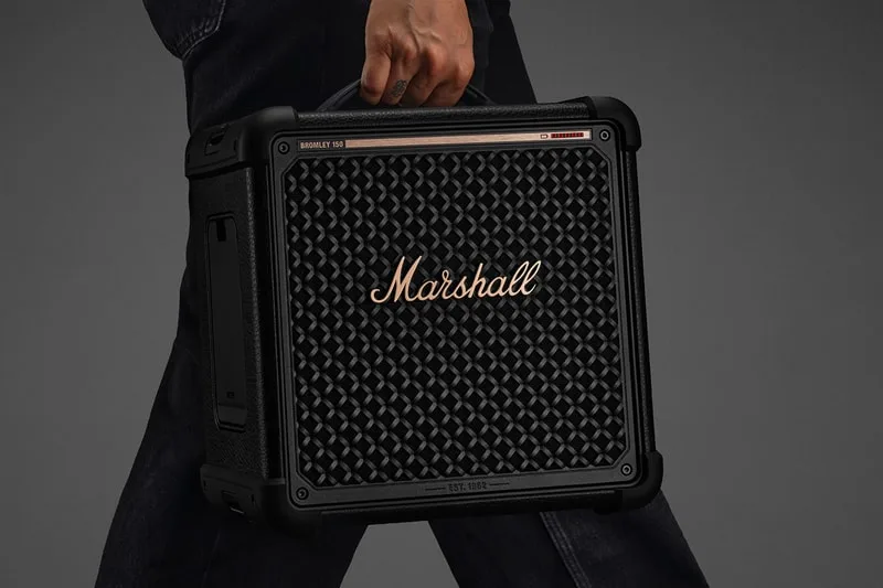 Ampli Marshall noir porté par une main d'une personne.
