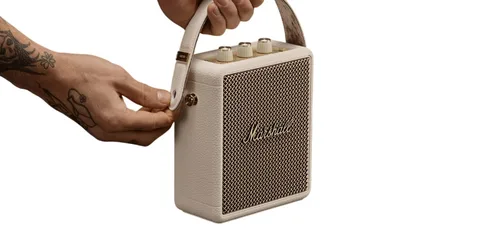 Haut-parleur portable blanc avec poignée et boutons dorés.