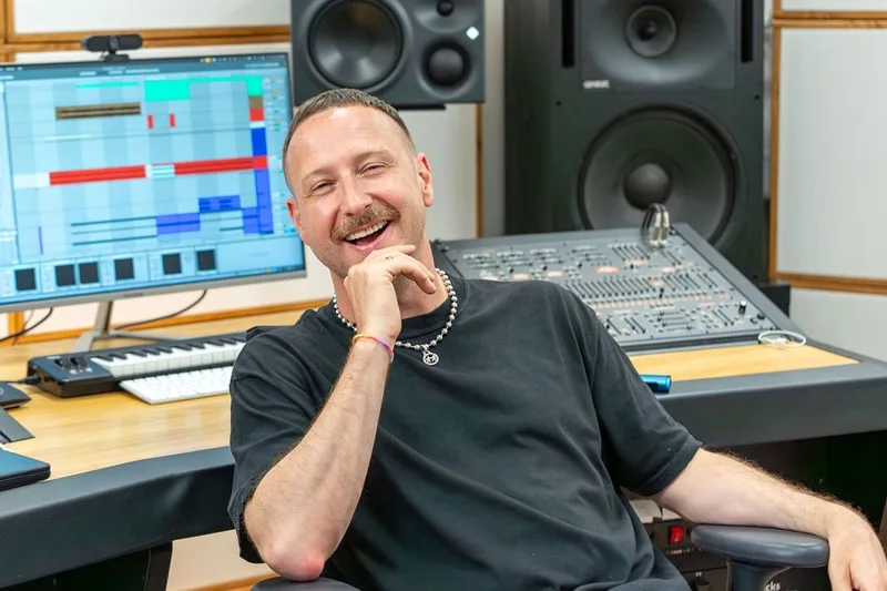 Homme souriant assis dans un studio d'enregistrement.