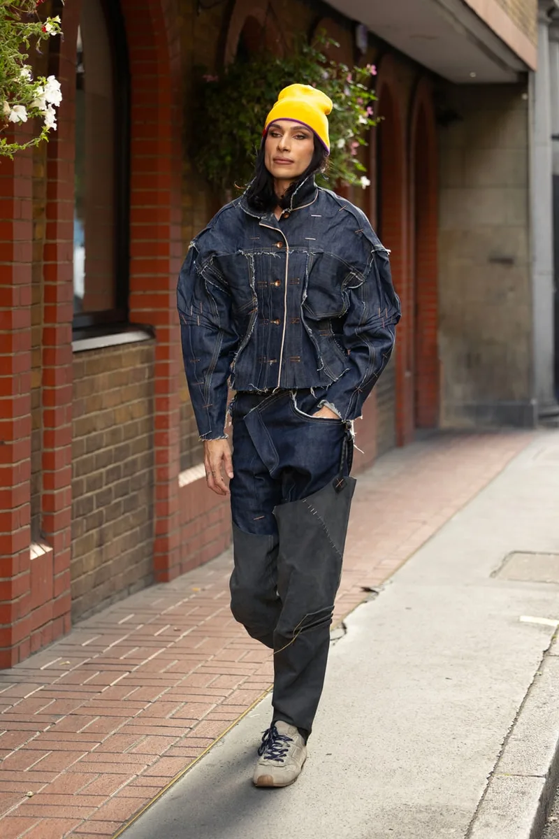 Personne portant une tenue en denim et un bonnet jaune dans la rue.