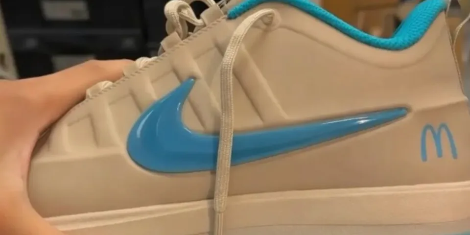 Basket beige avec logo bleu et McDonald's, main visible tenant la chaussure