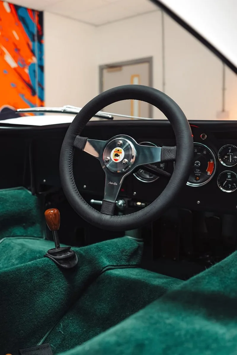 Intérieur d'une voiture vintage avec volant en cuir et moquette verte.