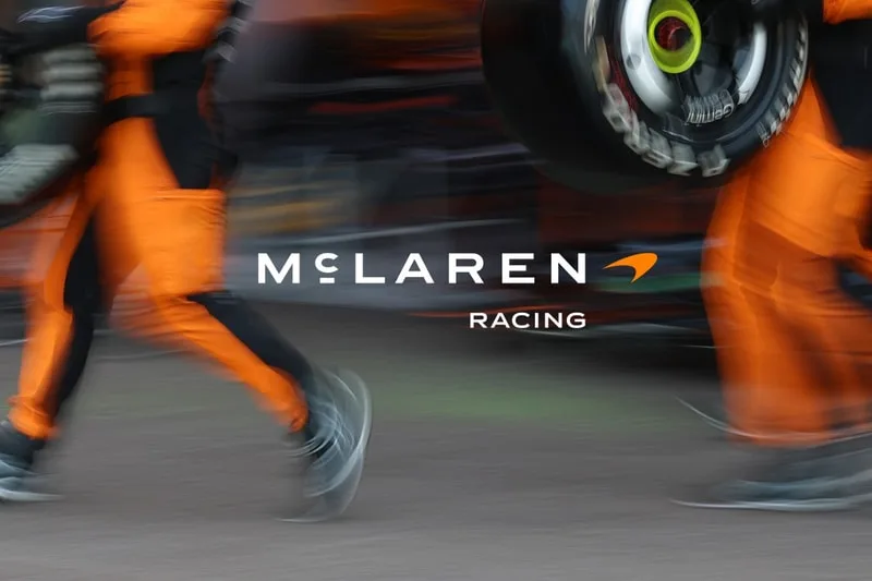 Logo de McLaren Racing flou avec des combinaisons orange.