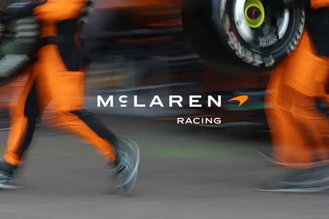 Logo de McLaren Racing flou avec des combinaisons orange.